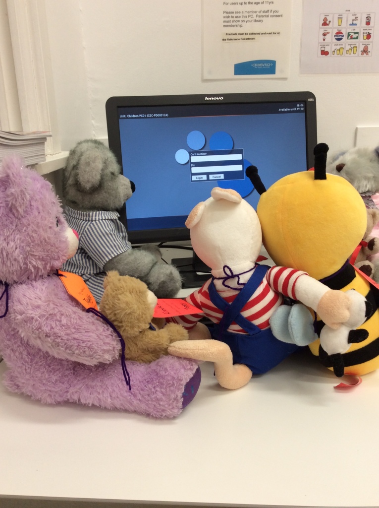 A group of teddy bears gathered around a computer screen.