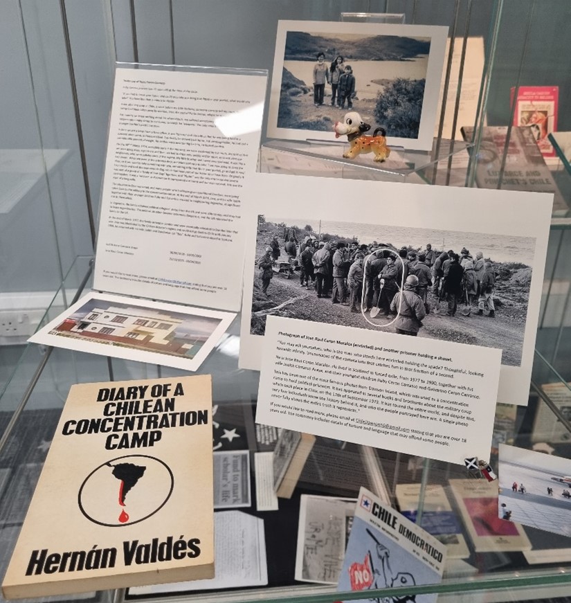 Detail of selection of books, images and papers on display in a glass cabinet.