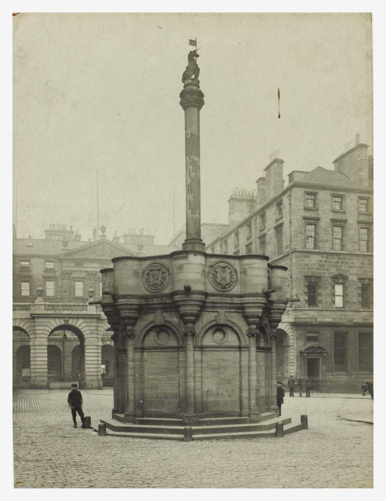 A stone carved unicorn sits atop the tall pillar above Edinburgh's mercat cross. 