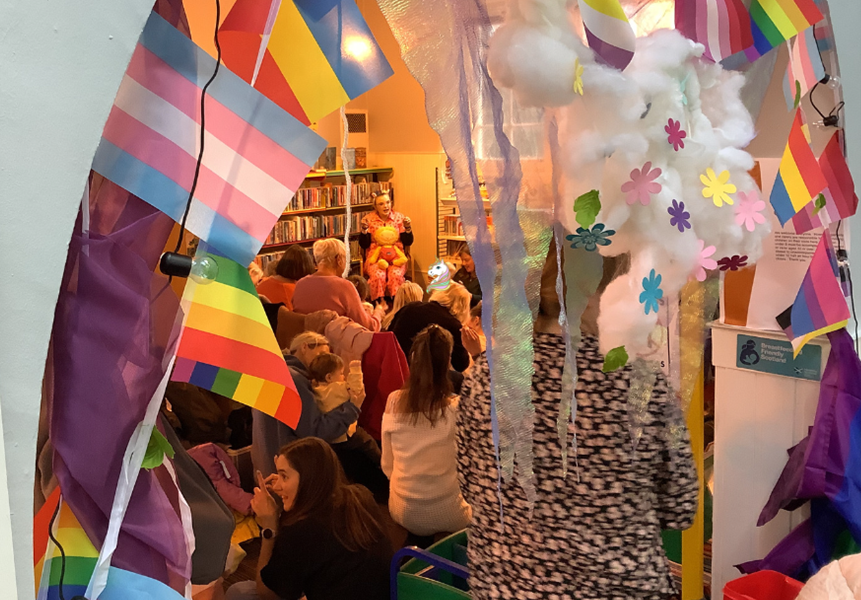 A Bookbug session for babies and their carers in a library decorated with rainbow flag bunting.