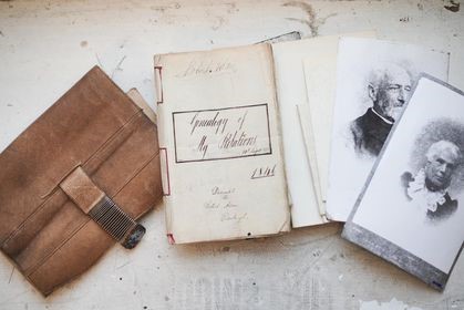 A leather wallet, documents and photos are displayed on a table. 