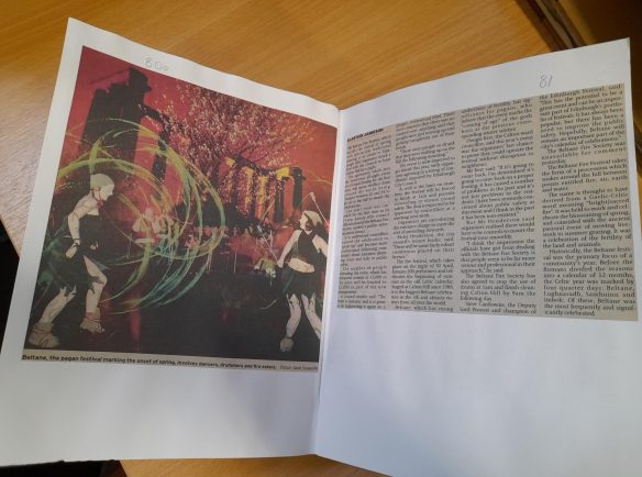 Open page from a bound volume of press cuttings showing a colourful image one side and newspaper print on the other.